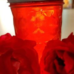 two red roses are sitting next to a jar