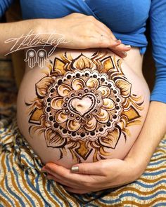 a pregnant woman's belly with henna tattoos on it