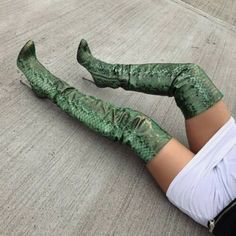 a woman is laying on the ground wearing green snakeskinned thigh - high boots