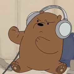 a brown teddy bear with headphones sitting on the floor in front of a wall