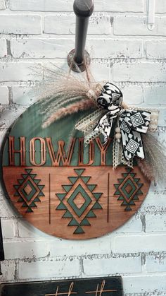 a wooden sign hanging on the side of a brick wall that says, howdy