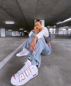 a woman sitting on the ground with her foot up in front of her face and wearing white sneakers