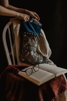 an open book sitting on top of a white chair next to a pair of glasses