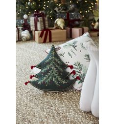 a christmas tree pillow sitting on the floor in front of a christmas tree and presents