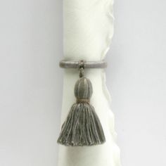 a white napkin with a tassel hanging from it's end and a silver ring on top