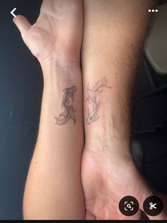 two people holding hands with tattoos on their arms and one has a fish tattoo on the wrist