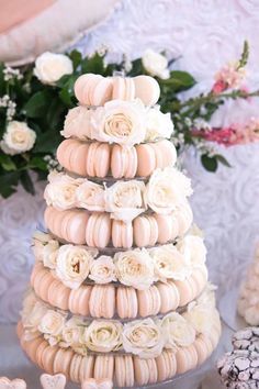 a wedding cake made out of macaroons and roses on a table with flowers in the background