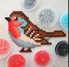 the bead bird is sitting next to several plastic containers with beads in each container