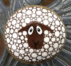 a decorated rock with a brown and white sheep's face painted on the top