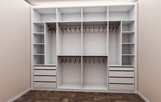 an empty white closet with clothes hanging on the shelves and drawers in front of it