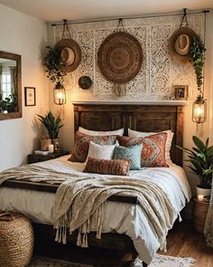 a large bed sitting in a bedroom next to two plants on top of a wooden headboard