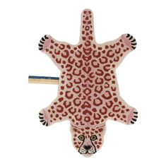 an animal shaped rug with red and black spots on it's face, next to a ruler