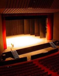 an empty theater with red curtains and lights on the stage, as seen from the front row