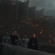 the cast of game of thrones standing in front of an old castle at night