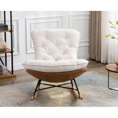 a white chair sitting on top of a wooden floor next to a book shelf filled with books