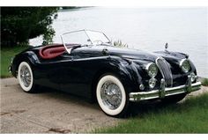 an old fashioned black car parked by the water