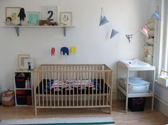 a baby's room with a crib, bookshelf and other items