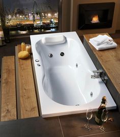 a bath tub sitting on top of a wooden floor next to a fire place in a bathroom