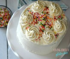 a cake with white frosting and sprinkles on it sitting on a plate