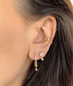 a close up of a woman's ear wearing gold and diamond earrings