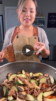 a woman in an apron is cooking mushrooms and zucchini