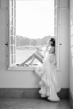 a woman is sitting on a window sill