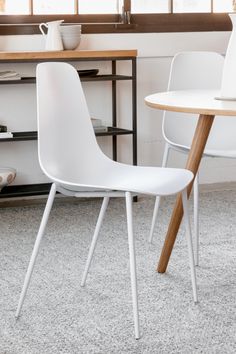 a white chair sitting next to a wooden table on top of a carpeted floor