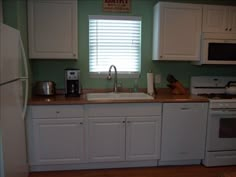 a kitchen with white cabinets and wood floors