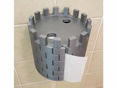 a toilet paper dispenser in the shape of a castle on a tiled wall