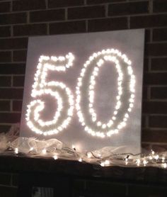 there is a sign that says 50 on it with lights around it in front of a brick wall