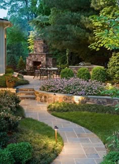 an outdoor patio with stone steps leading to a fire place and dining table in the background