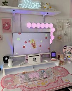 a desk with a computer monitor, keyboard and mouse on it in front of a neon sign