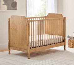 a baby crib in the corner of a room next to a window with white curtains