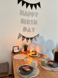 a table topped with plates and cake next to balloons