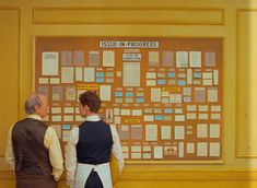 two people standing in front of a bulletin board