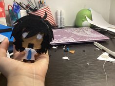 a person holding up a paper doll on a desk with other items in the background