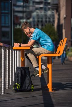 a young man sitting at an orange table writing