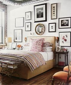 a bed sitting in a bedroom next to a window with pictures hanging on the wall