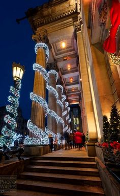 christmas lights adorn the steps leading to an ornate building