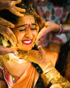 a woman is covered in yellow powder while she holds her hands up to her face