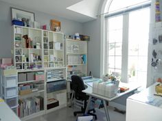 an office with lots of shelves and desks next to a large window in the room