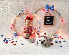 a baby sitting next to a dog on a bed