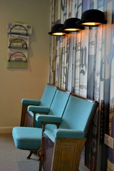 blue chairs are lined up in front of a wall with posters on it and lights above them