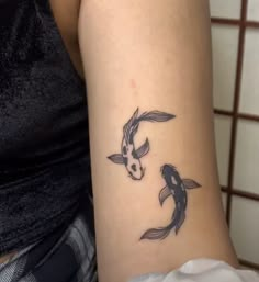 a woman's arm with two koi fish tattoos on it