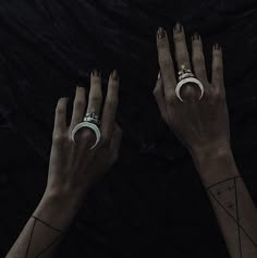 two hands with tattoos and rings on their fingers