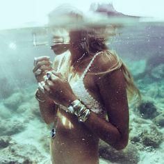 a woman standing under water holding a cell phone