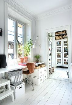 a white room with a desk, chair and bookshelf next to a window