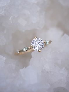 a diamond ring sitting on top of some ice flakes with one stone in the middle