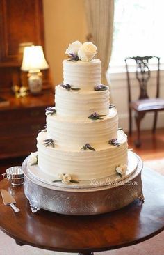 a wedding cake with white frosting and purple flowers