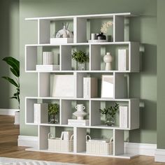 a white book shelf with many books and plants on it in the corner of a room